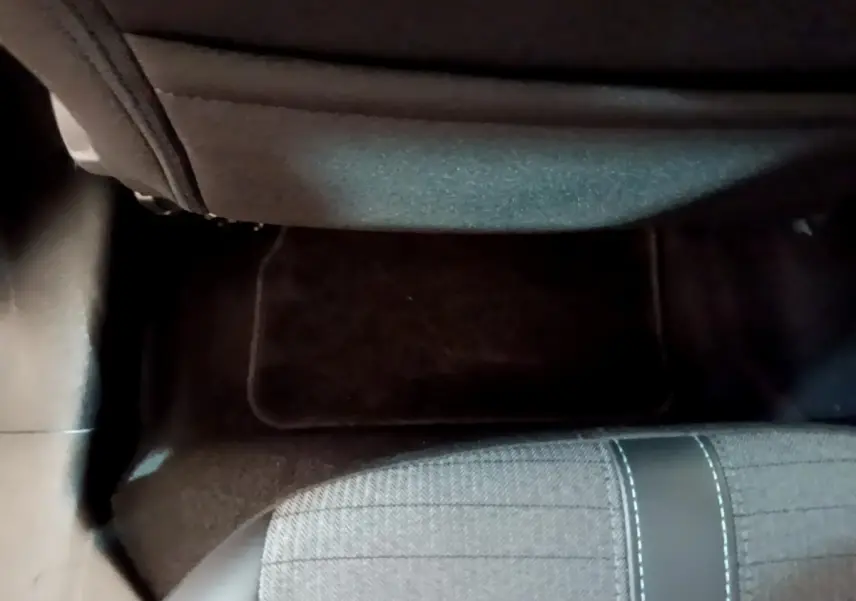 Vue plongeante sur le sol et l'assise arrière droite de la Peugeot 208 jaune, montrant la moquette et le tissu du siège.