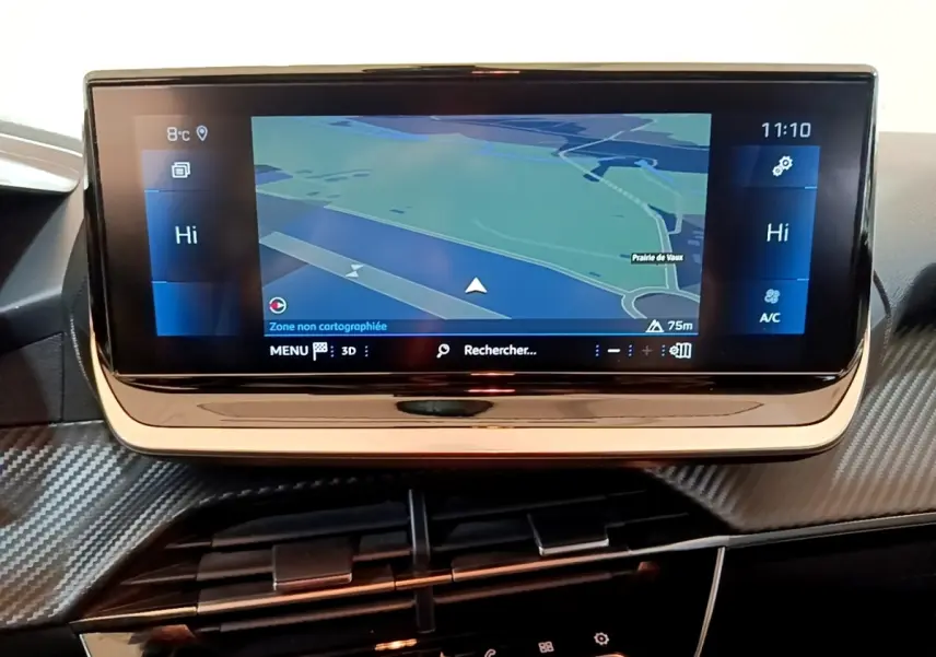 Écran tactile central de navigation affichant une carte, tableau de bord avec finition carbone dans une Peugeot 208.