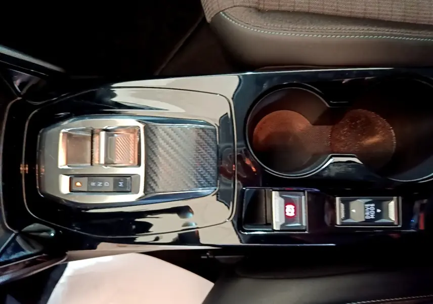 Vue plongeante sur la console centrale noire brillante de la Peugeot 208 jaune, avec la commande de boîte automatique et porte-gobelets.