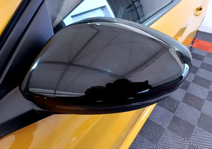 Rétroviseur noir en gros plan côté gauche d'une Peugeot 208 jaune PureTech 100 S&S EAT8 Allure Pack 2023.
