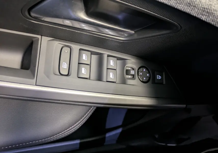 Gros plan sur la commande des vitres et rétroviseurs côté gauche intérieur du Peugeot 5008 blanc Okenite 2025.