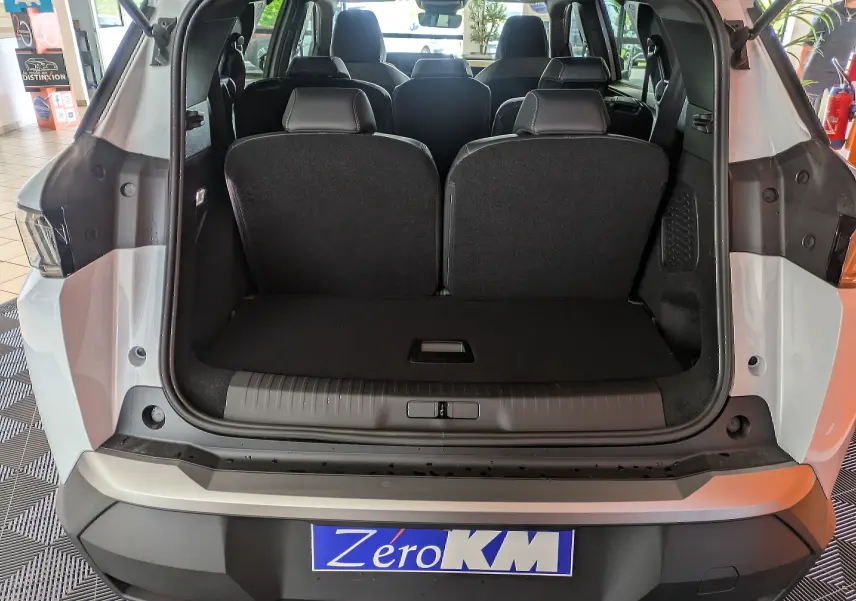 Coffre ouvert vue arrière du Peugeot 5008 blanc Okenite, montrant les sièges arrière et l'espace de chargement.