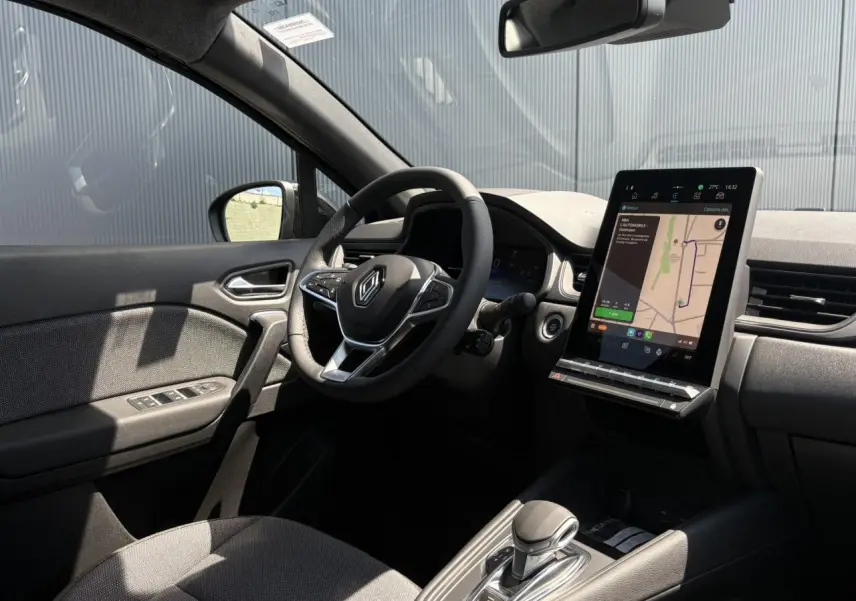 Intérieur noir du Renault Captur 2025, vue côté conducteur, volant multifonctions et écran tactile vertical avec navigation.