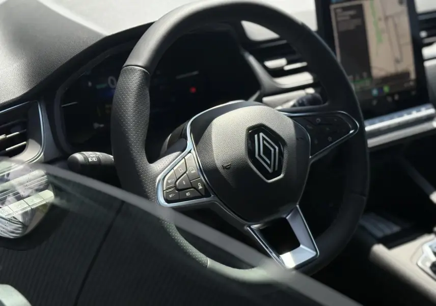 Gros plan sur le volant cuir multifonctions du Renault Captur 2025, avec tableau de bord et écran tactile en arrière-plan.