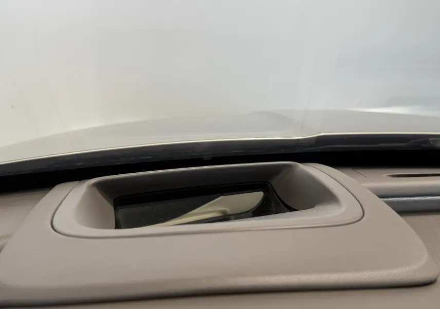 Détail du tableau de bord beige de la Jaguar XE 20d 2015 avec écran encastré sous le pare-brise.