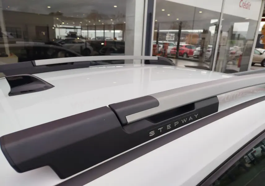Gros plan sur la barre de toit grise avec logo Stepway du toit blanc glacier d'une Dacia Sandero Stepway 2021.