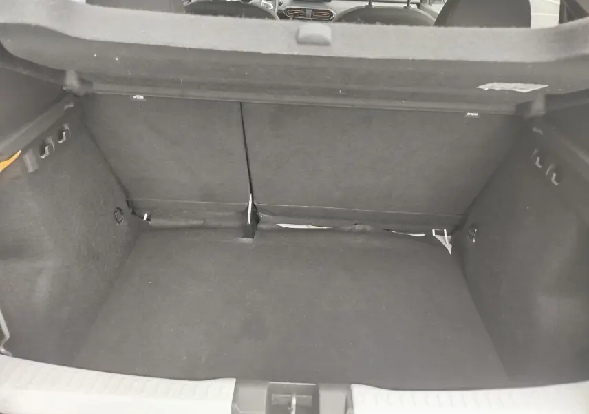 Coffre ouvert de la Dacia Sandero Stepway blanc glacier, vue intérieure arrière montrant l'espace de chargement vide.