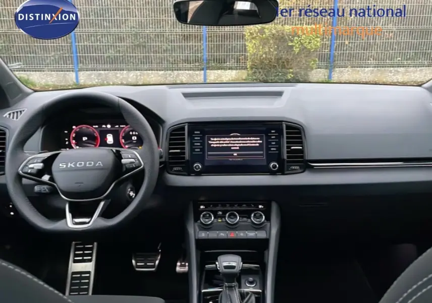 Vue intérieure frontale du tableau de bord noir et volant SKODA avec écran tactile et levier de vitesse automatique.