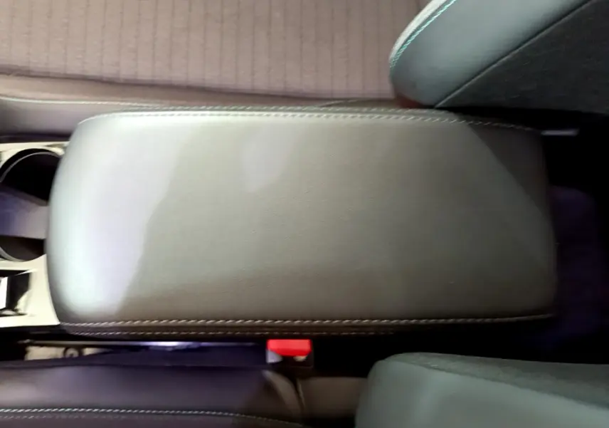 Vue rapprochée de l'accoudoir central en cuir gris foncé à surpiqûres blanches dans l'habitacle d'une Peugeot 2008.