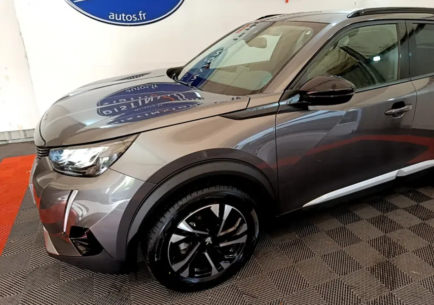 Vue 3/4 avant droit d’un Peugeot 2008 gris foncé avec jantes alliage noires et phares LED ellipsoïdaux.