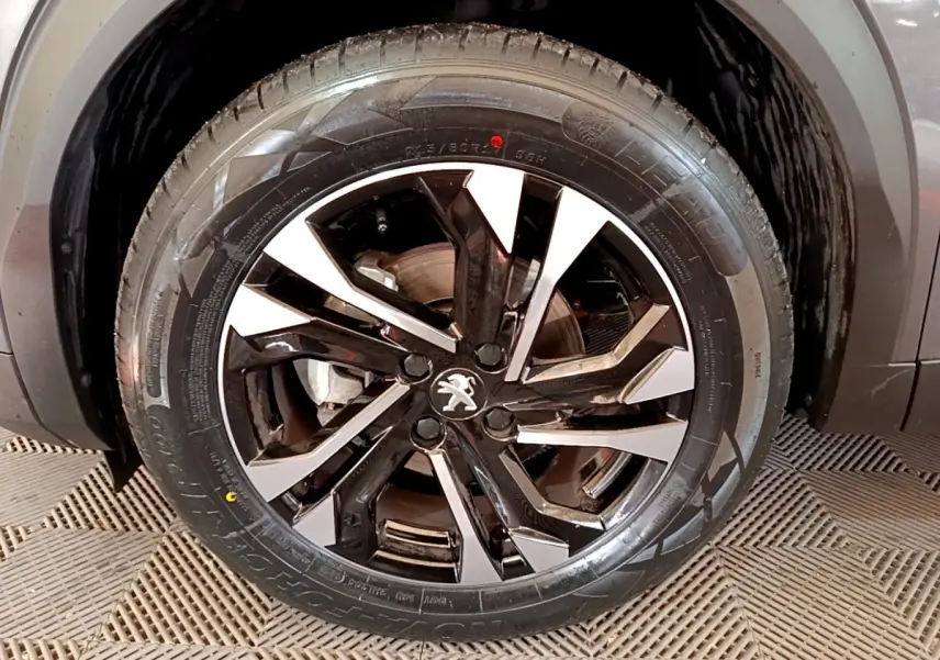 Gros plan sur la roue avant droite du Peugeot 2008 gris foncé, mettant en valeur la jante alliage bicolore au design moderne.