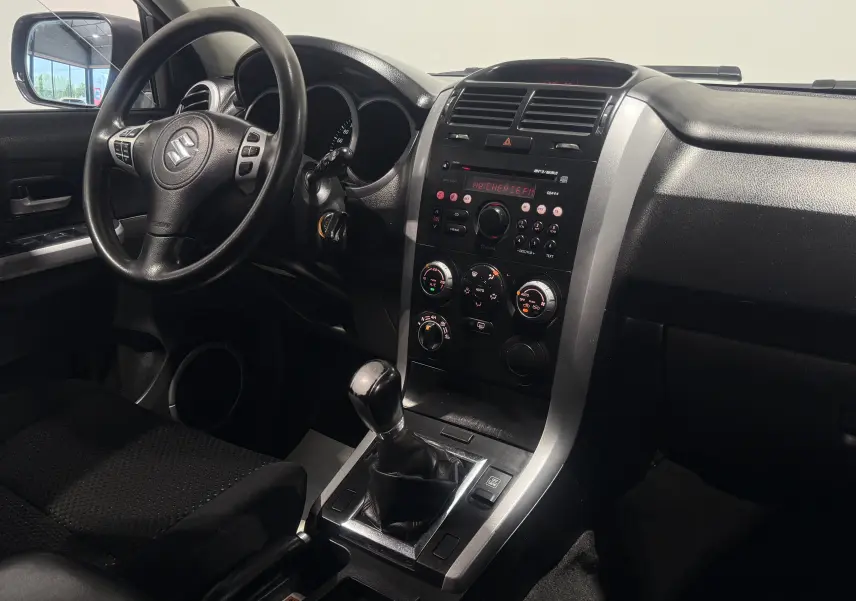 Intérieur du Suzuki Grand Vitara 2007 gris, vue du tableau de bord côté conducteur avec levier de vitesses manuel.
