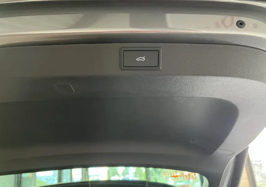 Bouton d'ouverture électrique du hayon du coffre sur un SUV SKODA KAROQ gris 2025, vue intérieure du hayon ouvert.
