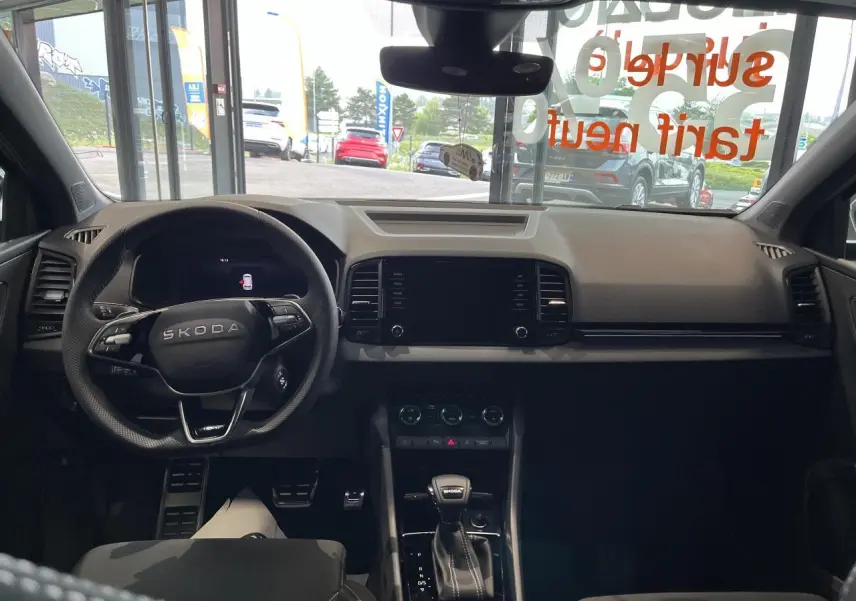 Intérieur du Skoda Karoq 2025 vu de face, tableau de bord noir avec volant sport multifonctions et levier DSG7.