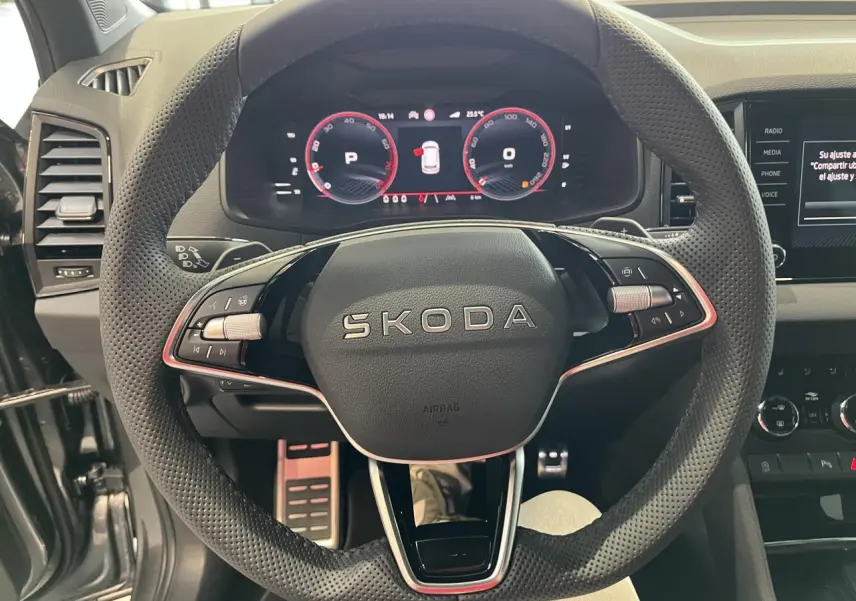 Vue rapprochée du volant perforé SKODA avec tableau de bord digital rouge et console centrale noire du KAROQ 2025 Sportline.