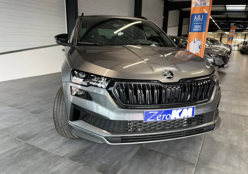 Vue avant rapprochée du SUV SKODA KAROQ gris métallisé avec calandre noire et phares LED en showroom.