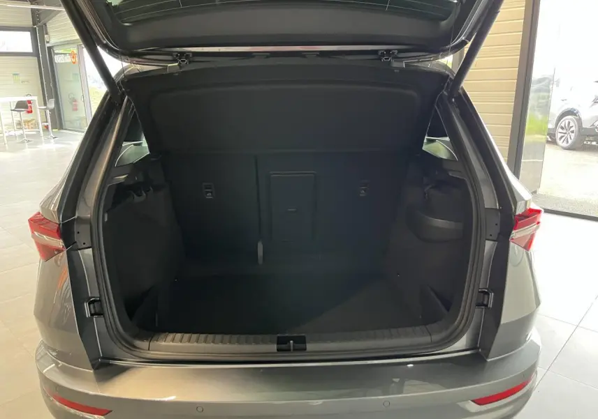 Coffre ouvert vu de l'arrière d'un SUV SKODA KAROQ gris avec hayon électrique dans un showroom.