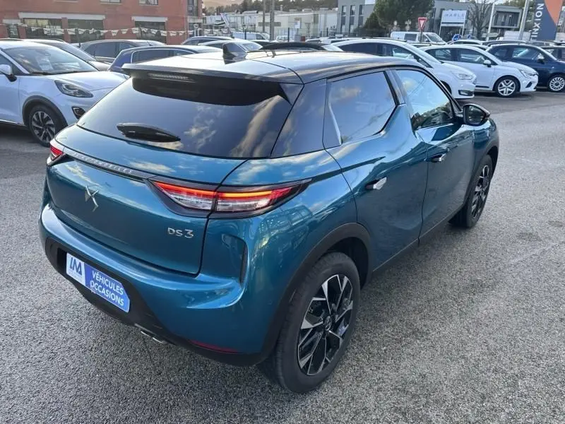 Vue 3/4 arrière droite d'une DS3 1.2 Hybride 145 Étoile bleu métal avec toit noir et feux arrière LED distinctifs.