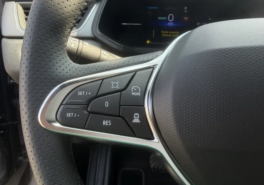 Gros plan sur les commandes gauche du volant textile perforé du Renault Captur 1.8 E-Tech hybride 2026.