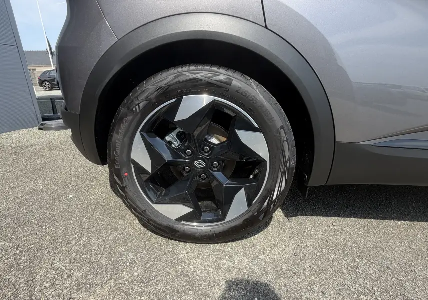 Gros plan sur la roue arrière droite du Renault Captur gris Cassiopée bi-ton avec jante aluminium 18 pouces au design étoilé.
