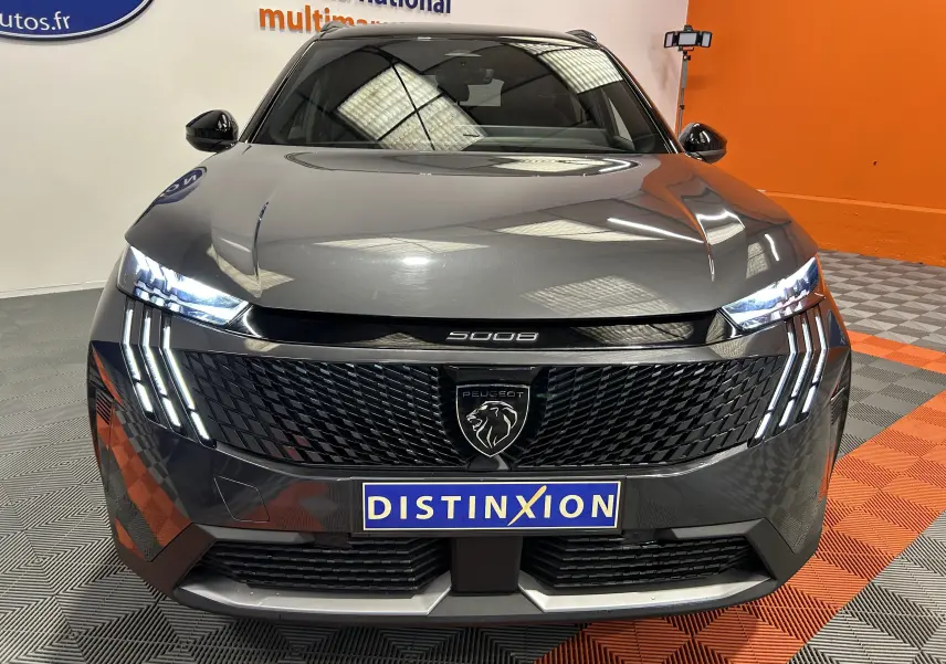 Vue avant rapprochée du Peugeot 5008 gris titane avec feux LED distinctifs et calandre noire brillante.