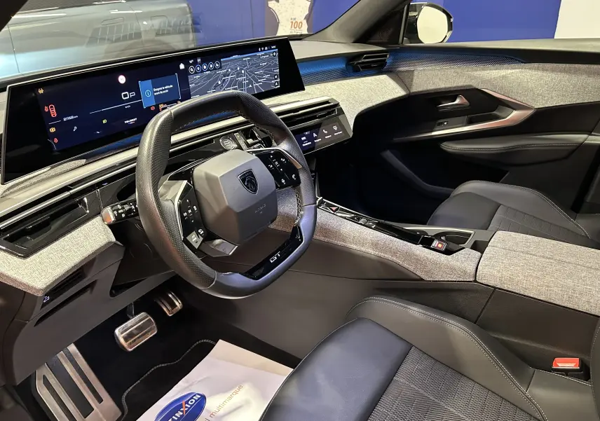 Vue intérieure côté conducteur du Peugeot 5008 III Hybrid 145 e-DCS6 GT, avec tableau de bord numérique et sellerie noire.
