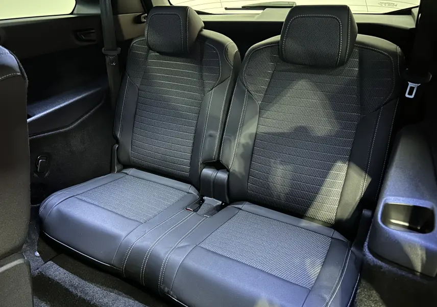 Vue rapprochée des sièges arrière en tissu et cuir noir avec surpiqûres blanches du Peugeot 5008 III Hybrid 2025.