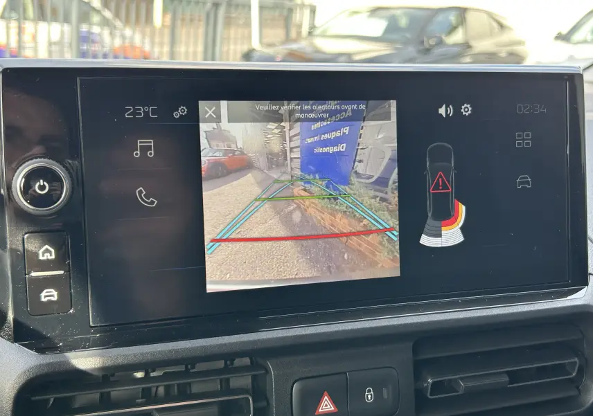 Écran tactile du Peugeot Partner Fourgon blanc montrant la caméra de recul avec guidage et alertes de proximité.