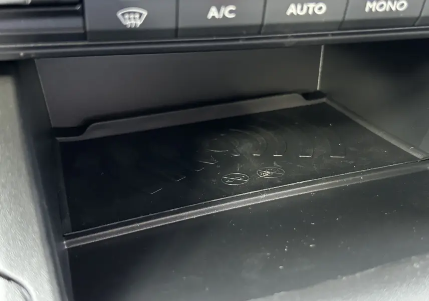 Détail du compartiment de recharge sans fil sous les commandes de climatisation du Peugeot Partner Fourgon blanc.