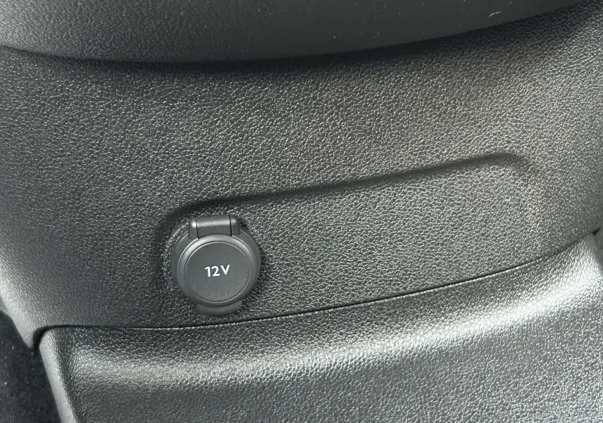 Prise 12V en gros plan sur la console intérieure noire du Peugeot Partner Fourgon blanc 2025.