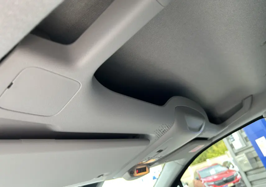 Détail du plafond intérieur gris clair du Peugeot Partner Fourgon avec pare-soleil baissé et vitre avant visible.