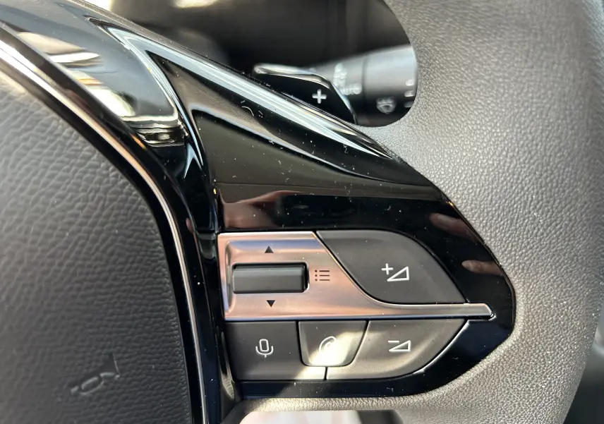 Gros plan sur les commandes du volant côté gauche du Peugeot Partner Fourgon blanc 2025 avec boutons multifonctions.