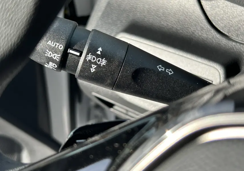 Gros plan sur la manette de clignotant noire du Peugeot Partner Fourgon 2025, avec pictogrammes blancs visibles.