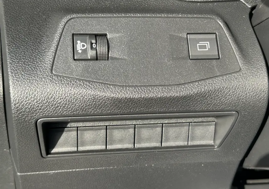 Détail des commandes de réglage d'éclairage et bouton multifonction sur tableau de bord noir du Peugeot Partner Fourgon blanc.