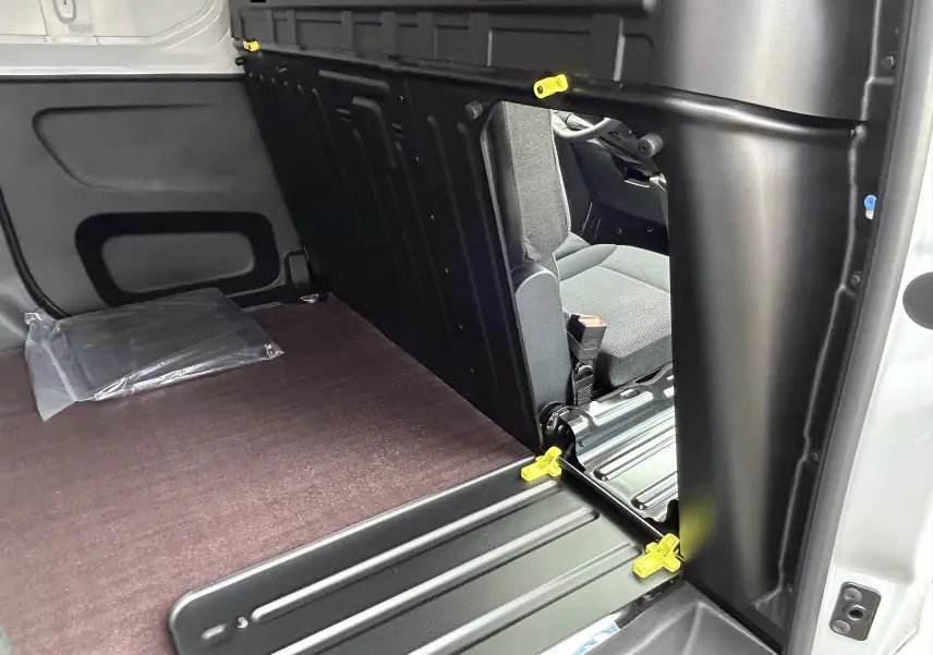 Intérieur du Peugeot Partner Fourgon blanc, vue du plancher bois et cloison séparative côté droit du véhicule.