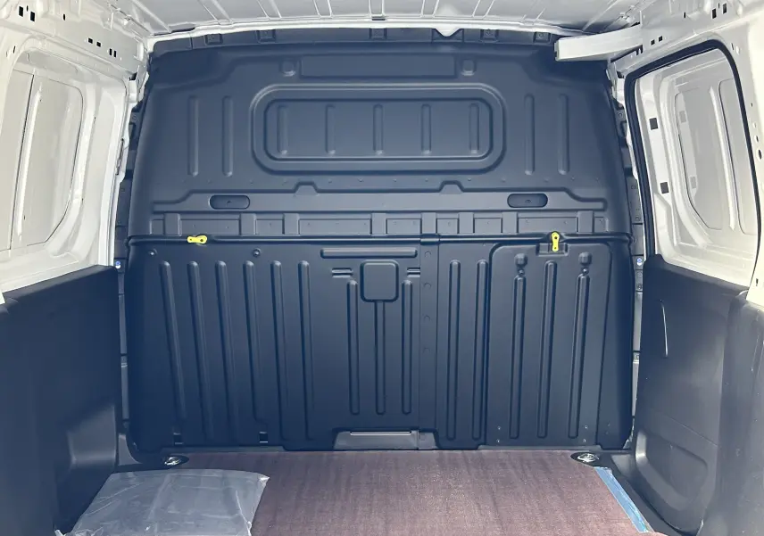 Vue intérieure arrière du Peugeot Partner Fourgon blanc 2025 avec plancher bois et parois noires renforcées.