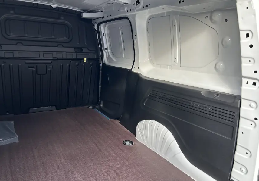 Intérieur du fourgon Peugeot Partner blanc, vue latérale droite montrant le plancher bois et parois noires.