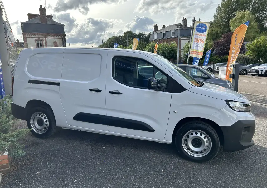 Vue de profil côté droit d'un Peugeot Partner Fourgon blanc avec poignées et rétroviseurs noirs sur parking extérieur.