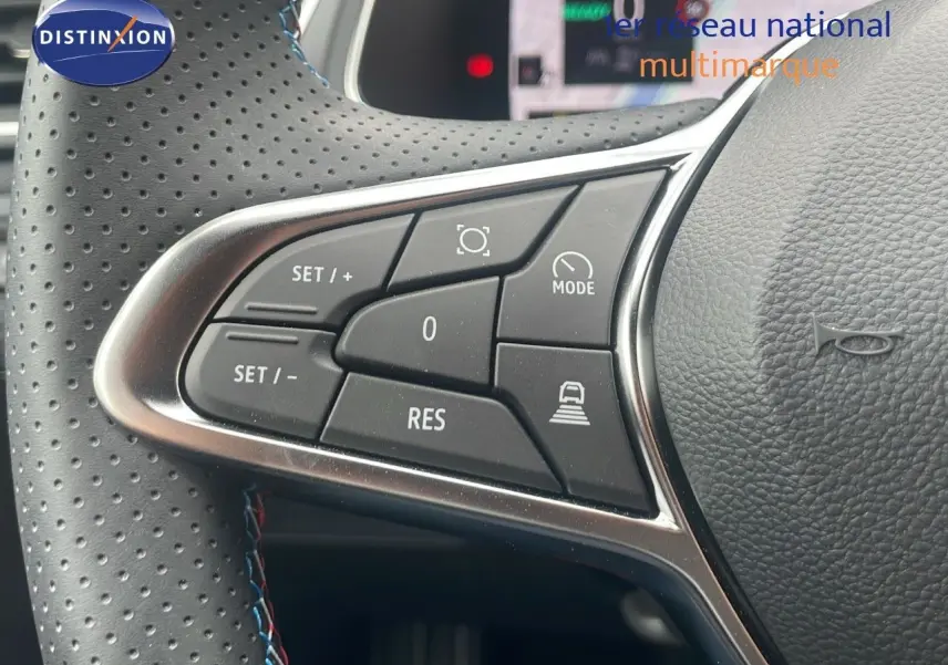 Gros plan sur les commandes au volant en cuir perforé noir du Renault Captur E-Tech hybride blanc nacré toit noir.