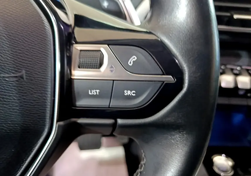 Gros plan sur les commandes gauche du volant noir du Peugeot 3008 blanc hybride rechargeable, version 2020 Allure.