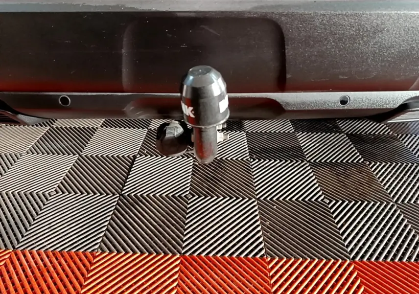 Gros plan sur l'attelage noir à l'arrière d'un Peugeot 3008 blanc, posé sur un sol à damiers noir et rouge.