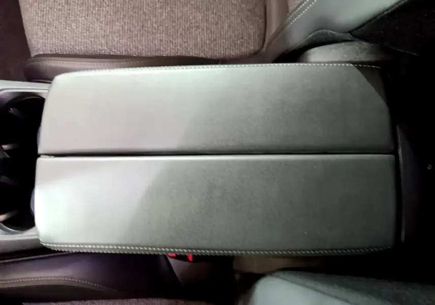 Vue rapprochée de l'accoudoir central en cuir noir à surpiqûres blanches dans l'habitacle du Peugeot 3008 blanc hybride.