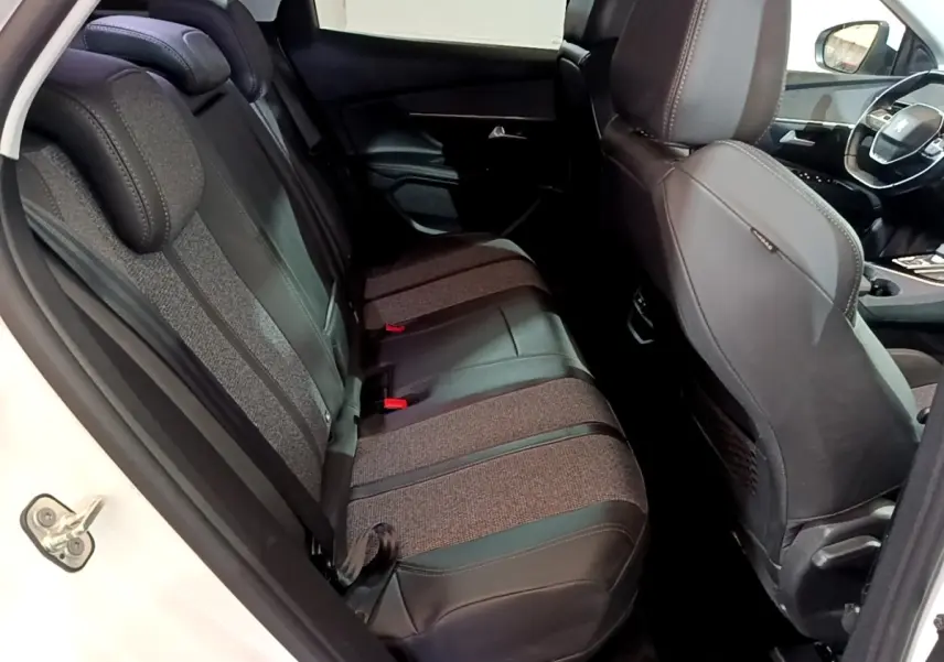Vue intérieure côté arrière droit du Peugeot 3008 blanc, montrant les sièges arrière en tissu et cuir bicolore.