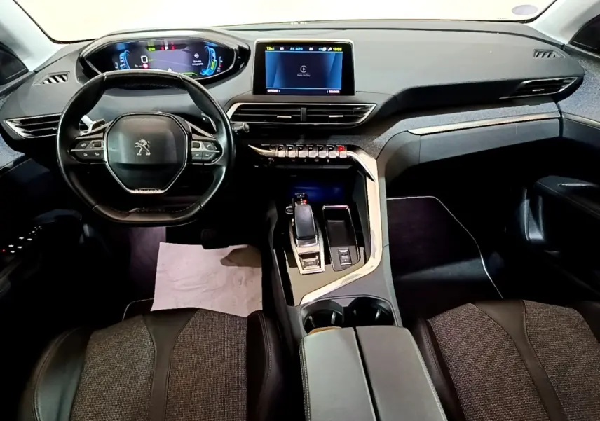 Vue intérieure avant du Peugeot 3008 hybride blanc, tableau de bord numérique et console centrale avec levier de vitesses.