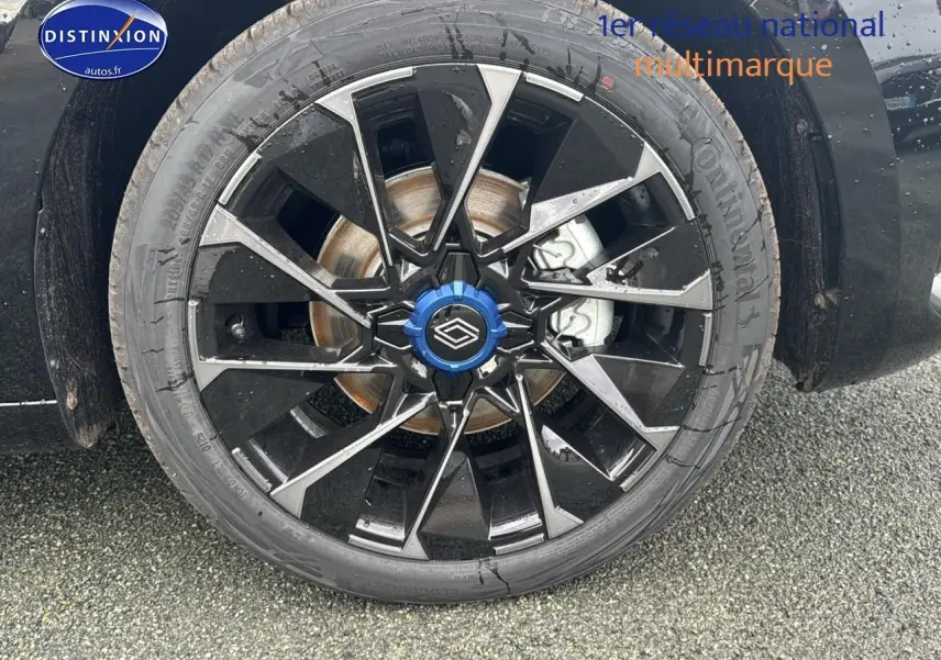 Gros plan sur la jante alu 17 pouces esprit alpine noire et argentée avec capuchon bleu d'une Renault Clio V noir étoile.