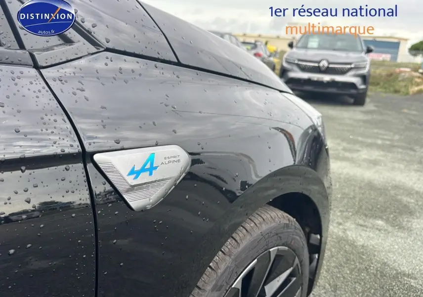 Gros plan sur l'aile avant gauche noire étoile d'une Renault Clio V esprit Alpine avec logo bleu distinctif.