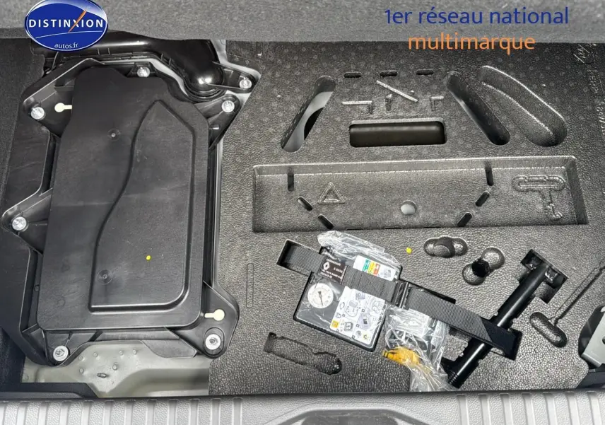 Gros plan sur le compartiment de rangement sous le coffre de la Renault Clio V noire étoile avec kit de réparation pneus.