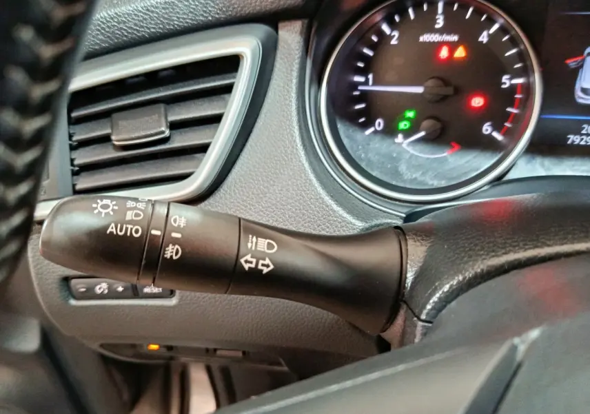 Gros plan sur la commande des phares et clignotants à gauche du volant dans le tableau de bord du Nissan Qashqai gris clair 2019.