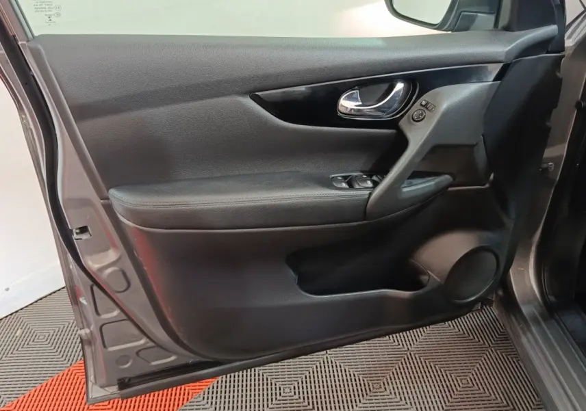 Porte avant gauche ouverte d'un Nissan Qashqai gris clair, montrant le panneau intérieur noir avec commandes électriques.