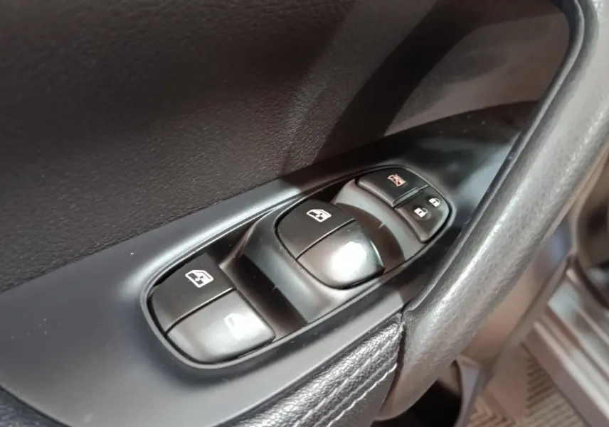 Gros plan sur les commandes des vitres électriques côté conducteur dans l'habitacle noir du Nissan Qashqai gris clair 2019.